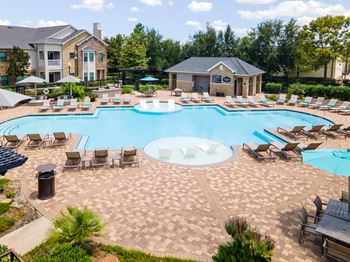 A large outdoor swimming pool surrounded by lounge chairs and umbrellas.
